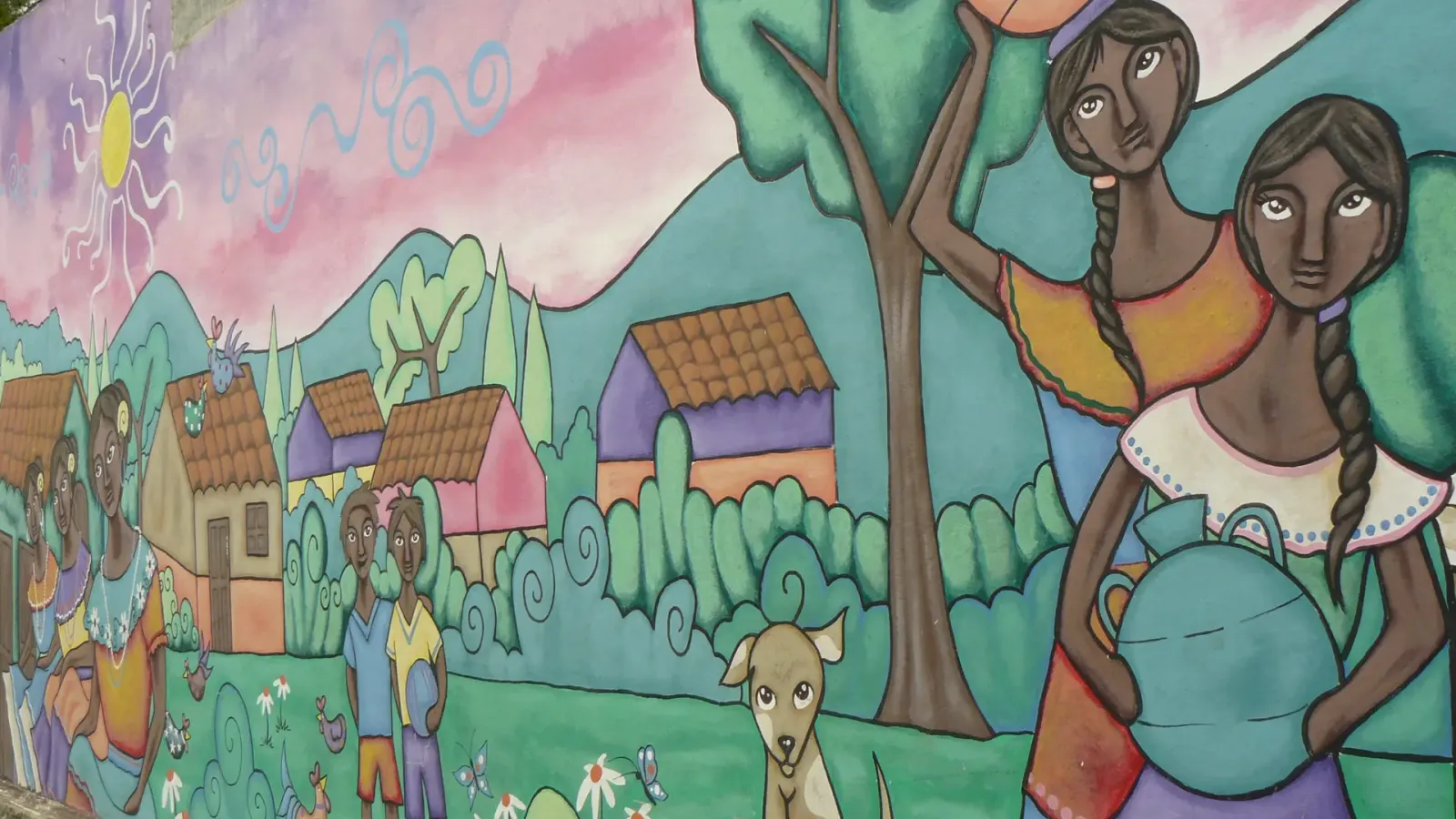A painted street mural at Concepcion de Ataco showing two women carrying a water jar and fruit past village houses and a dog.
