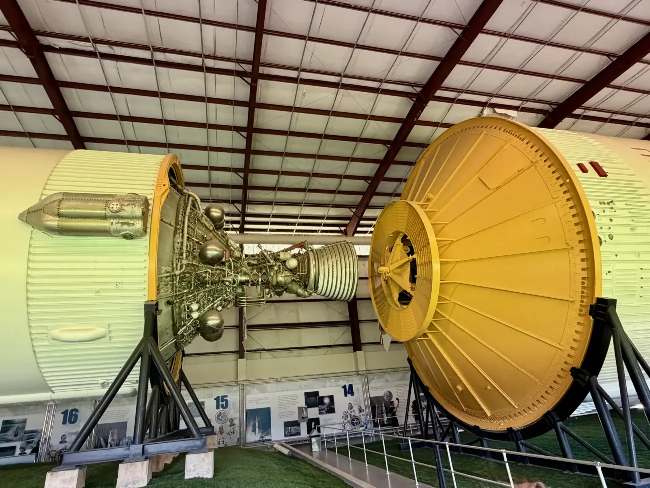 The stages and engines of a Saturn V moon rocket displayed end to end inside a long exhibit hall.