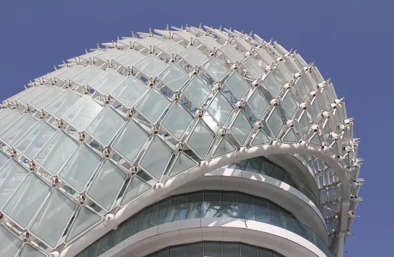 A curved glass and steel gridshell canopy over a hotel tower on Yas Island, Abu Dhabi