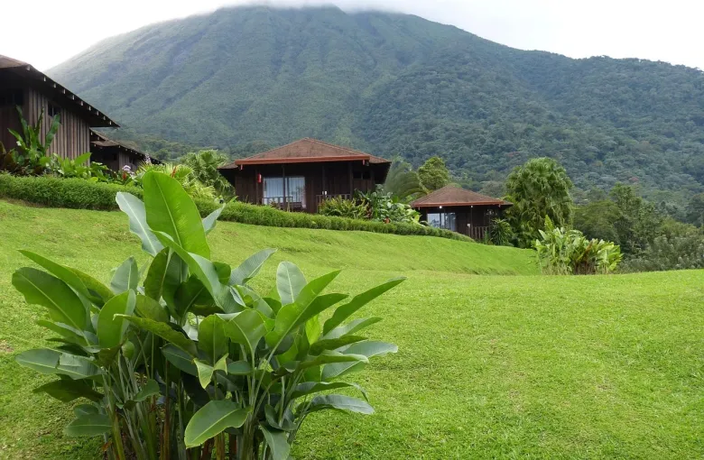 Lodge grounds and lawns below the forested cone of Arenal Volcano in Costa Rica.