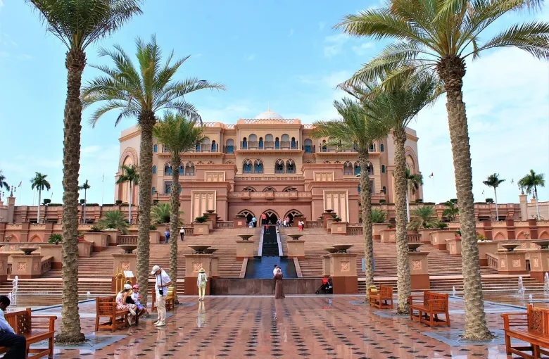 The palm-lined entrance courtyard and domed facade of Emirates Palace in Abu Dhabi.