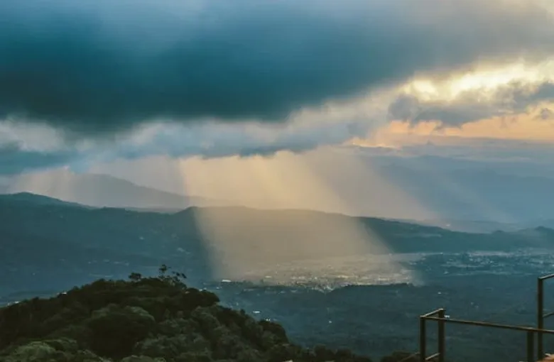 Mist and shafts of light over forested hills in the Costa Rican highlands.