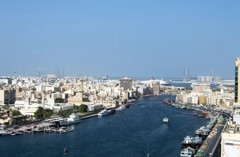 An aerial view of Dubai Creek with wooden dhows moored along the wharfage.