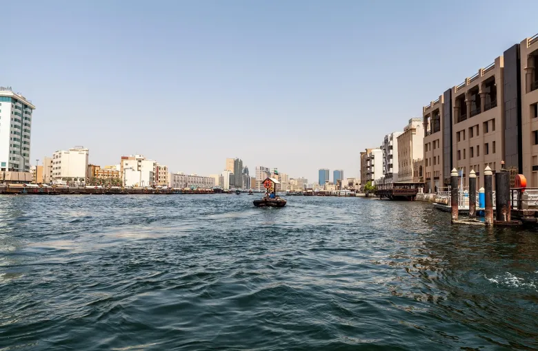Dubai Creek with the old quarter along the waterfront and boats crossing the channel.