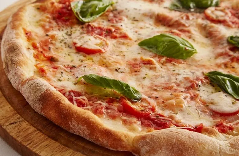 A margherita pizza with fresh basil leaves on a wooden board
