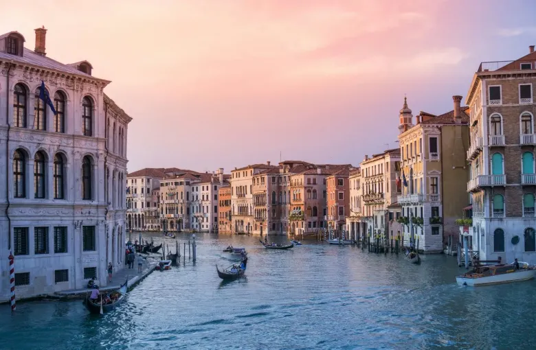 The Grand Canal at dawn, lined with Venetian palazzi under a pink sky