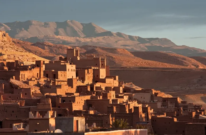 A ksar of packed earth towers rising in tiers on a hillside below the Atlas mountains.