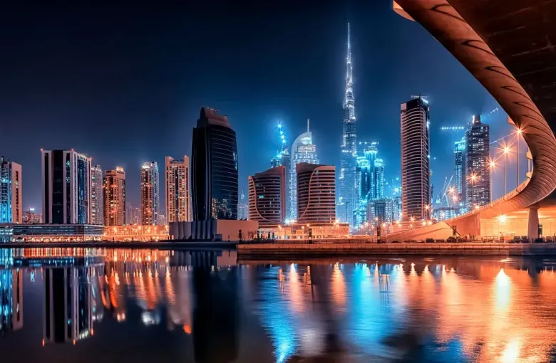 The Dubai skyline lit at night and mirrored in still water.
