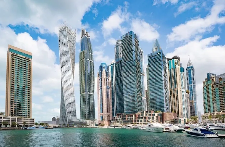 The towers of Dubai Marina reflected in the water beside moored boats.
