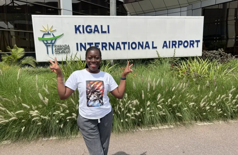 Traveler flashing peace signs at Kigali International Airport sign; Rwanda; during the eat-mea-2024 trip.