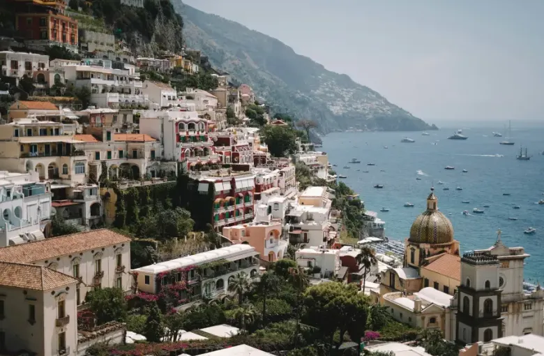 Colorful cliffside buildings of Positano overlooking the Tyrrhenian Sea with yachts anchored; ideal for group cruises alon...