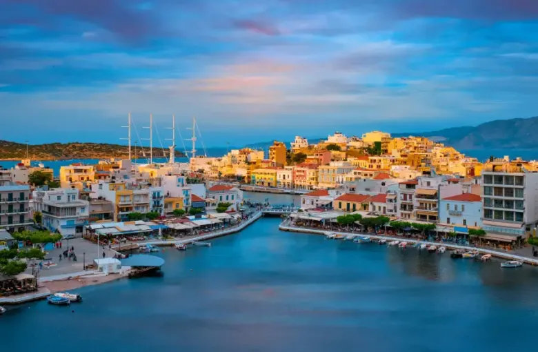 Colorful Mediterranean harbor town at sunset with sailboats docked; ideal backdrop for group cruises and corporate travel...