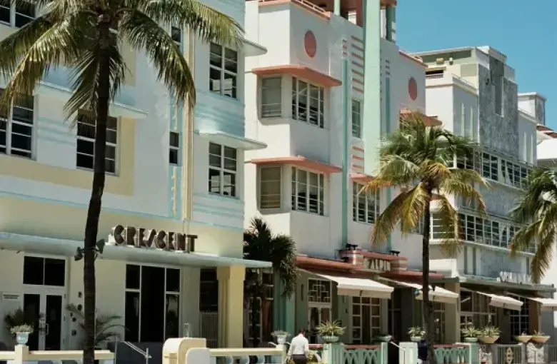 Art Deco hotels including the Crescent and Alpin line Ocean Drive in Miami Florida; flanked by palm trees under a clear bl...