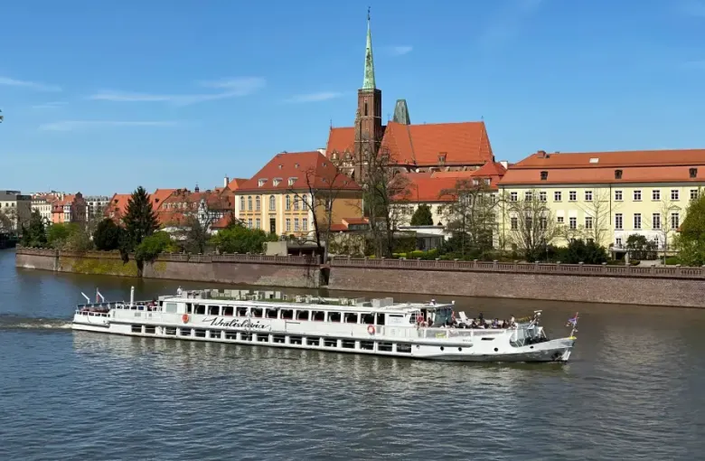Wratislavia cruise boat sailing the Oder River in Wrocław; Poland; with Collegiate Church of the Holy Cross in background.