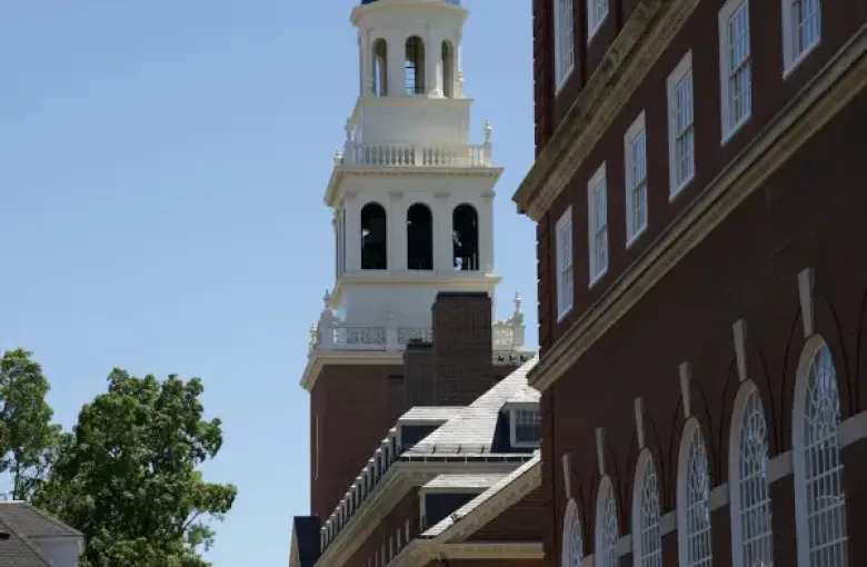 Independence Hall tower with white steeple rising above brick buildings in Philadelphia.