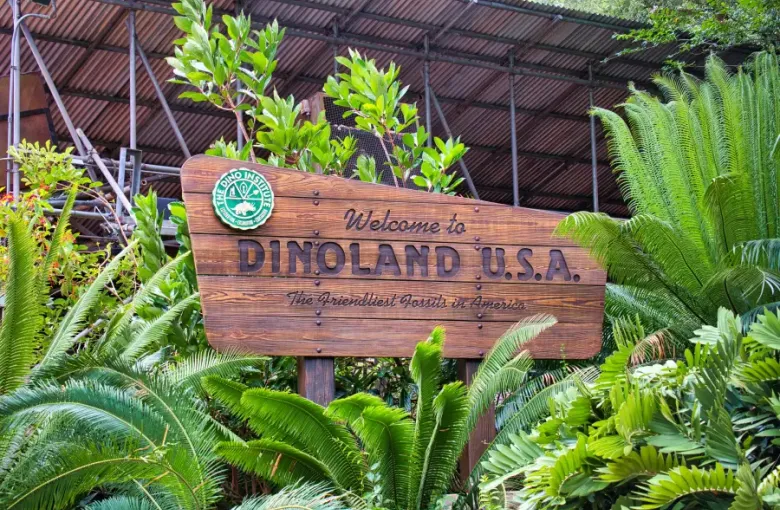 Wooden welcome sign for Dinoland U.S.A. at Disney's Animal Kingdom in Orlando; FL; surrounded by lush tropical ferns.