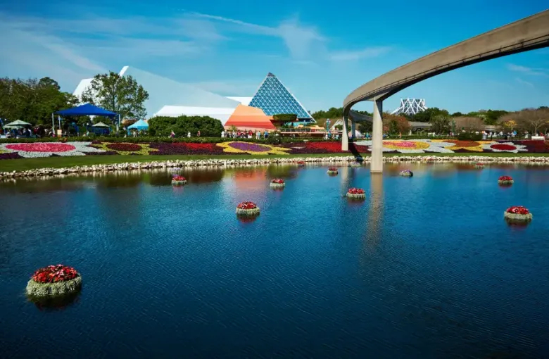 EPCOT's World Discovery pavilion and monorail reflected in lagoon with floating floral displays during Orlando; FL flower...