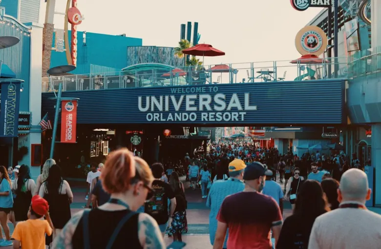 Crowds walk beneath the Welcome to Universal Orlando Resort sign in Orlando, Florida at dusk