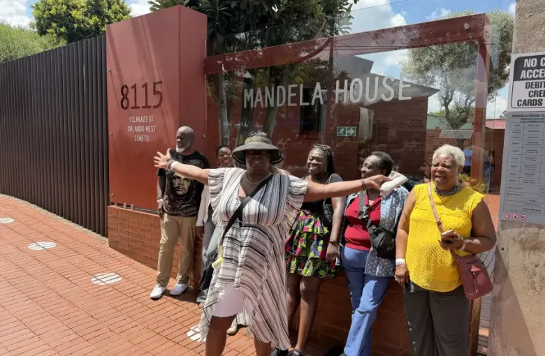 Group of travelers posing joyfully at the entrance of Mandela House; 8115 Vilakazi Street; Orlando West; Soweto; Johannesburg.