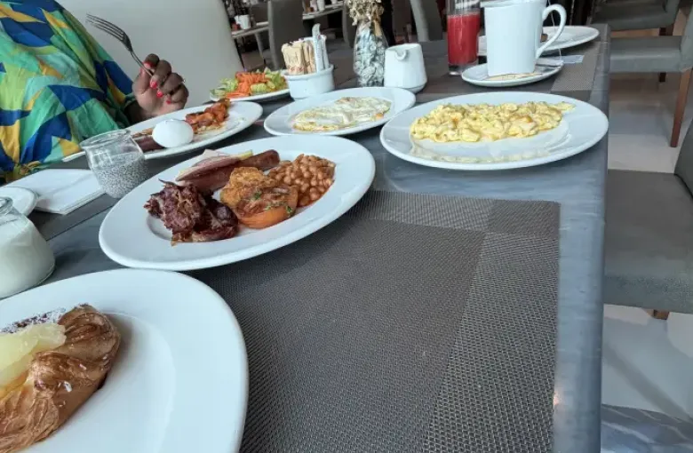 Elegant hotel breakfast spread in Doha Qatar featuring scrambled eggs; full English; pastries; juice; and coffee on a gray dining table.