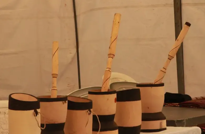 Carved wooden mortars and pestles displayed under a tent at a Botswana cultural festival.