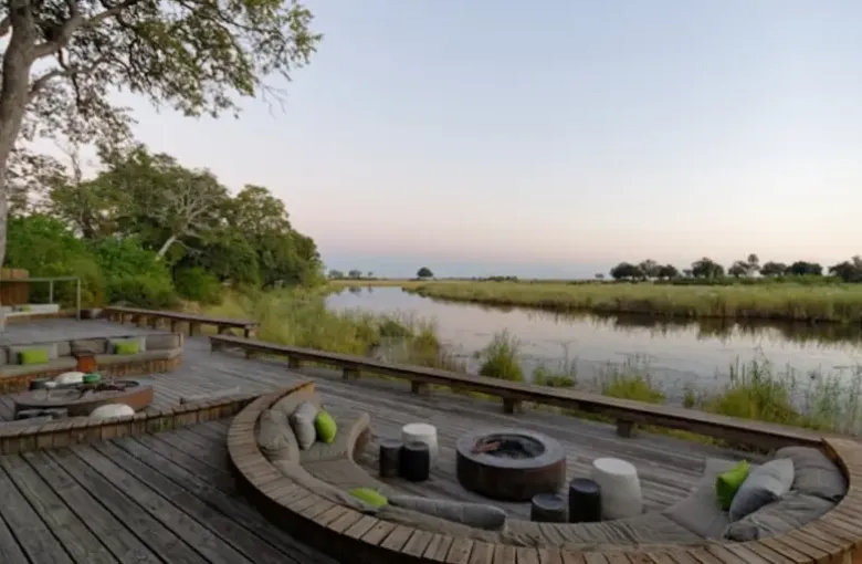 A raised wooden lodge deck with seating looking out over a floodplain.