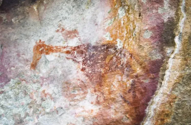 An ochre rock painting of a giraffe on weathered stone at the Tsodilo Hills.