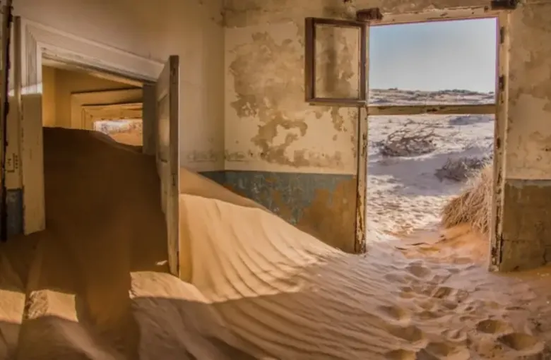Sand drifted deep through the doorway of an abandoned room at the Kolmanskop ghost town.