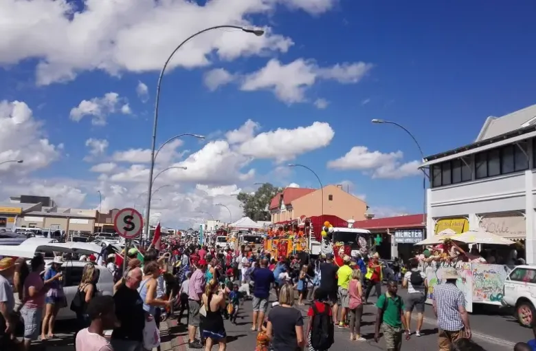 Crowds lining a Windhoek street during a carnival parade under a bright sky.