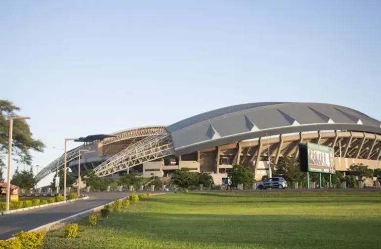 National Heroes Stadium in Lusaka Zambia seen from a palm-lined boulevard.