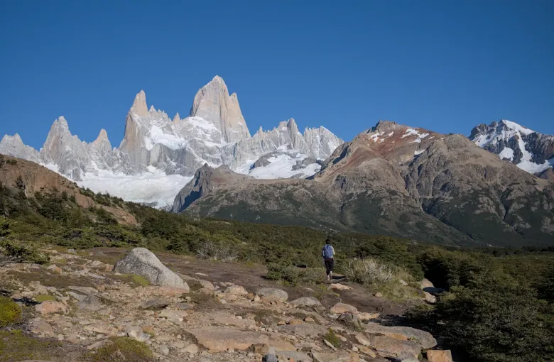 The granite spires of the Fitz Roy massif above scrub and bare rock in Los Glaciares National Park.