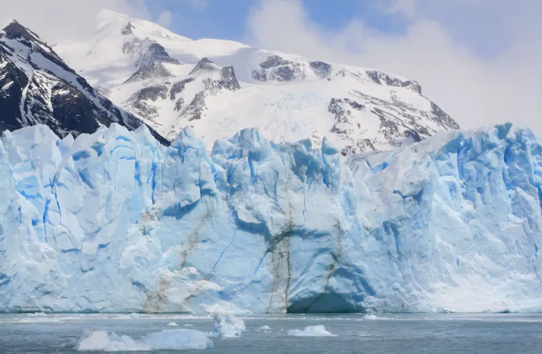 The crevassed blue and white front of the Perito Moreno Glacier meeting the water in Los Glaciares National Park.