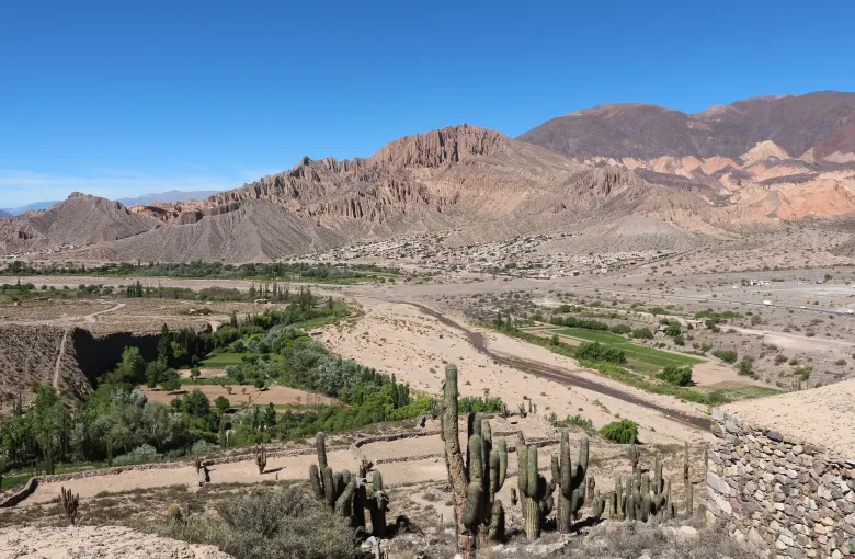 The banded red and ocher rock walls of the Quebrada de Humahuaca rising above the valley floor near Tilcara.