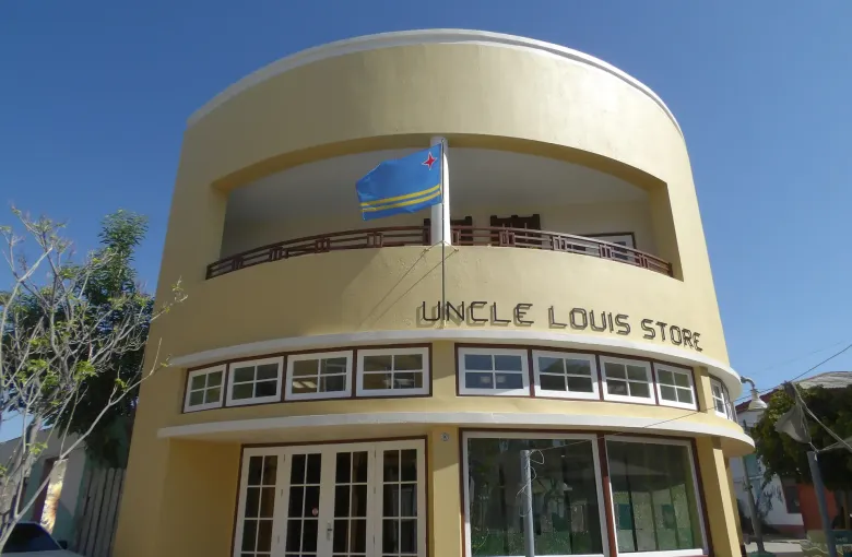 The cream art deco corner of Uncle Louis Store in Aruba, the national flag flying from its upper floor.