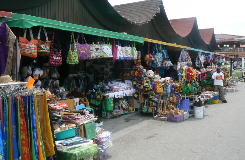 A covered market row in Aruba hung with woven bags, straw hats and bright sarongs.
