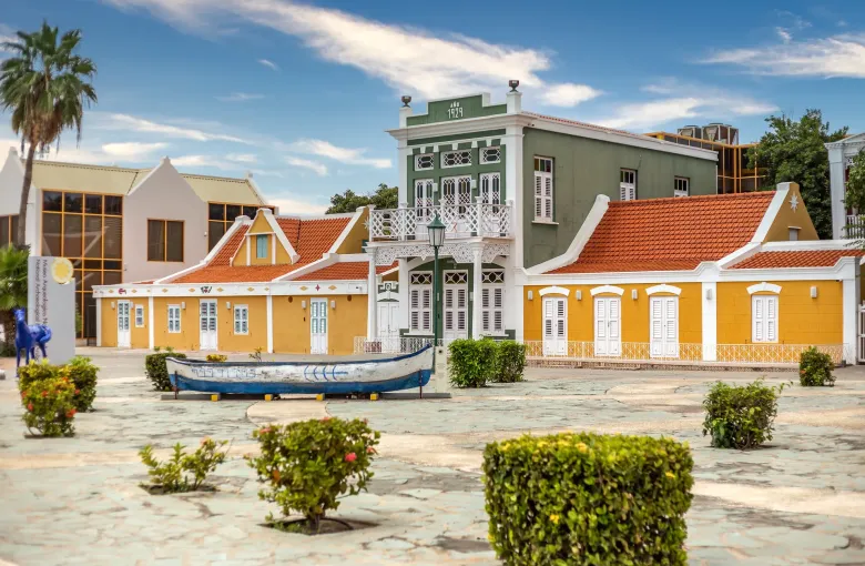Yellow and white Dutch colonial buildings with tiled roofs around the museum plaza in Oranjestad.