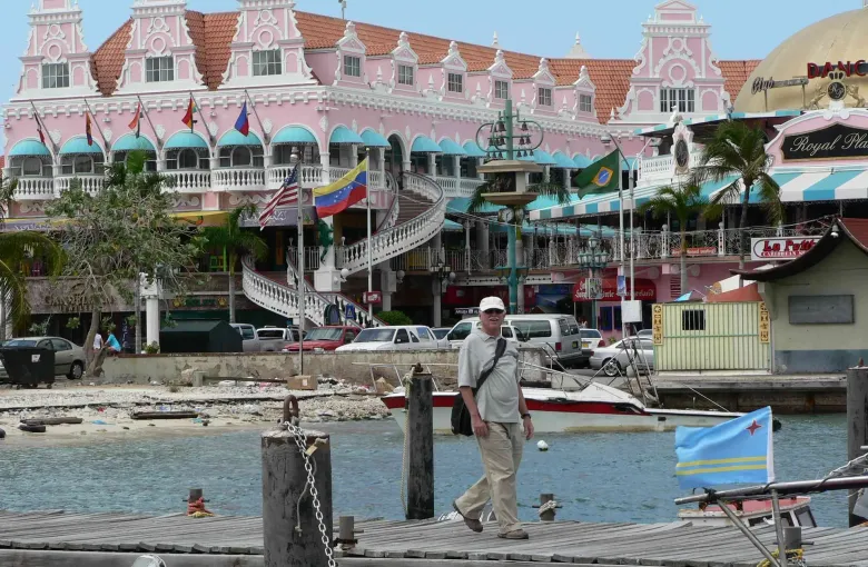The pink Dutch-gabled facade of Royal Plaza above the Oranjestad waterfront, with the Aruban flag flying.