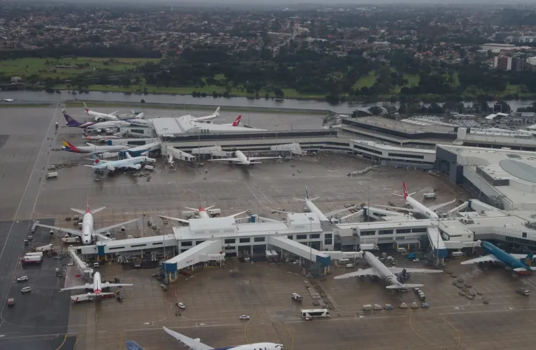 An aerial view of Sydney Airport's international terminal with aircraft parked at its gates.