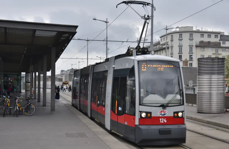 A low-floor Vienna tram standing at a raised street-level platform at Hauptbahnhof, its doorways level with the pavement.