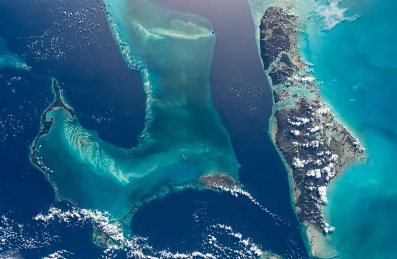 The Bahamas from orbit: pale shallow banks, deep blue channels and scattered cumulus over the islands.