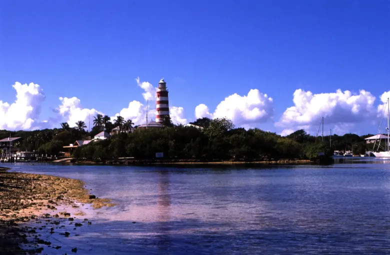 The red and white banded Elbow Reef Lighthouse rising over Hope Town harbor on Elbow Cay, Abaco.