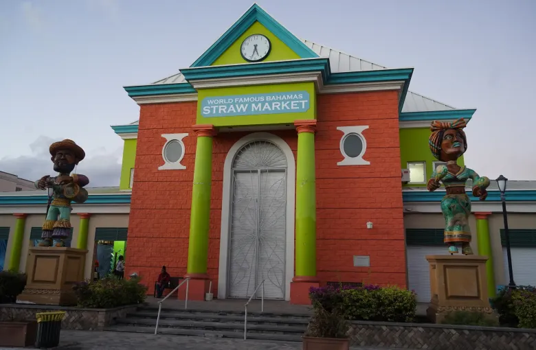 The brightly painted Straw Market building in Nassau, flanked by two large carved Junkanoo figures.