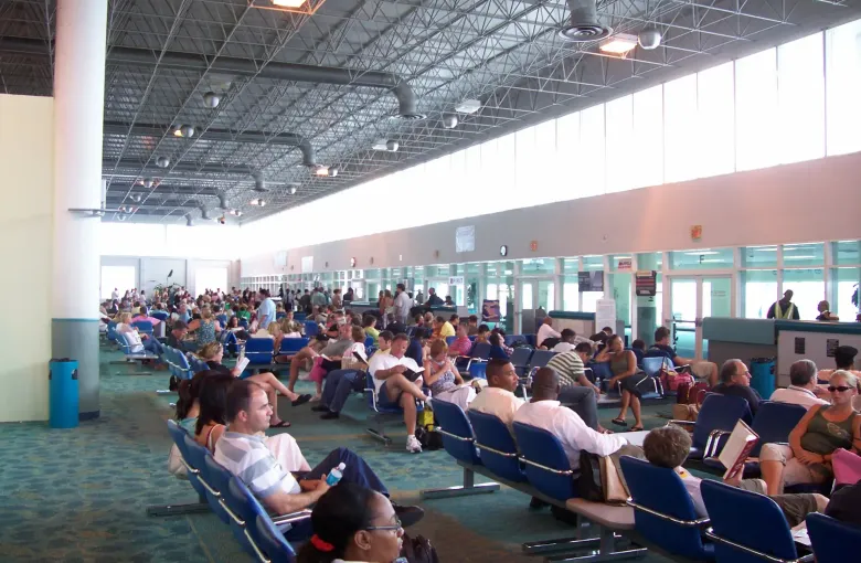Travelers waiting in rows of seating in the US departures hall at Nassau airport.