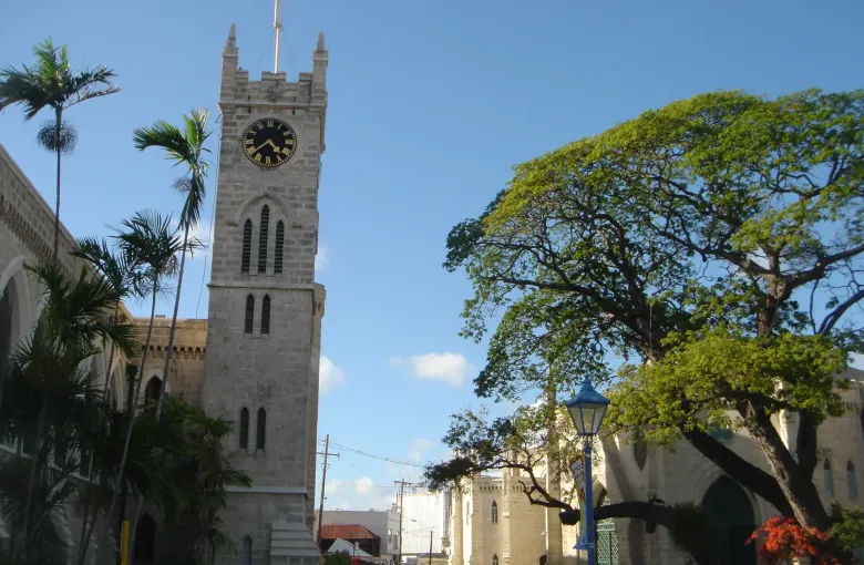 The clock tower of the Parliament Buildings rising above a street of shops in Bridgetown, Barbados.