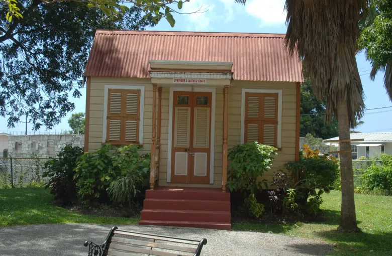 A restored timber chattel house with a red roof at the Tyrol Cot heritage village in Barbados.