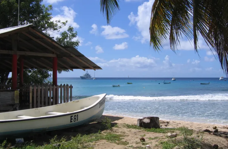Small boats moored offshore under a bright sky on the west coast of Barbados in Saint Peter.