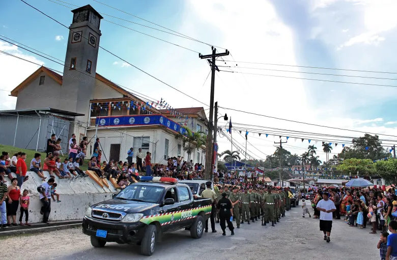 Crowds lining a bunting-strung street to watch an Independence Day parade pass in Belize.