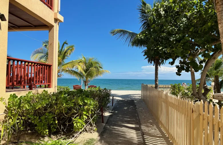 A level sand and concrete path running between a building and a fence to the beach at Placencia.