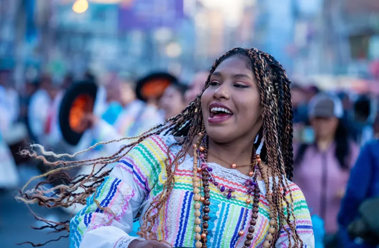 An Afro-Bolivian dancer in an embroidered blouse turns mid step during a saya performance at a La Paz parade.