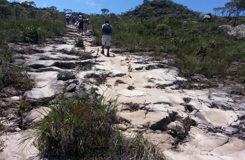 A walker on a bare rock trail crossing open scrub in the Chapada Diamantina in Bahia.